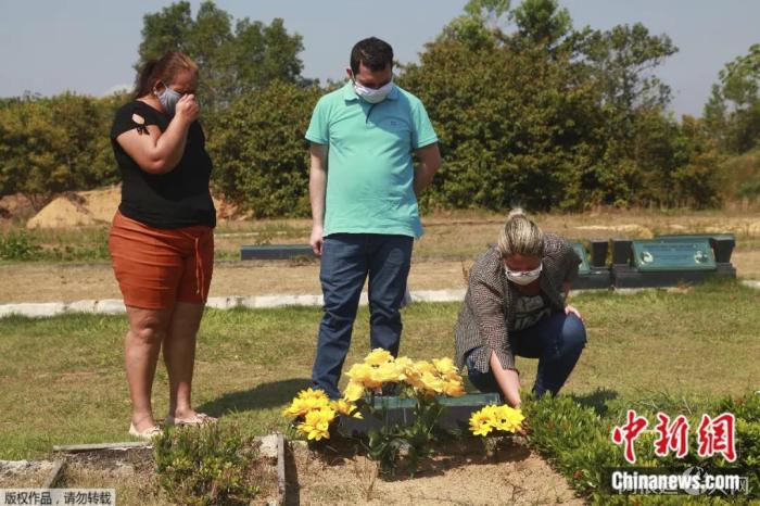 8月4日,在巴西玛瑙斯的一个墓地,亲属缅怀新冠逝者。 点击进入下一页