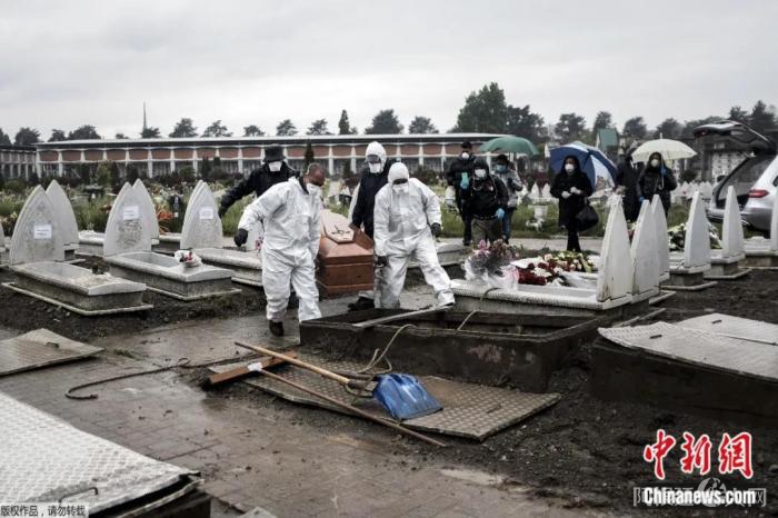 4月20日,在意大利都灵的墓地,身穿防护服的殡仪馆工作人员搬运棺材准备下葬。 点击进入下一页