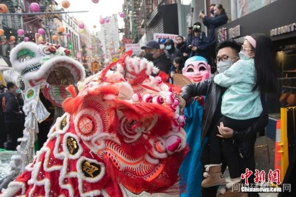2月12日，美国纽约曼哈顿唐人街举行春节庆祝活动，民众聚集唐人街欢庆新春。图为一位父亲带着女儿触摸舞狮。 中新社记者 廖攀 摄