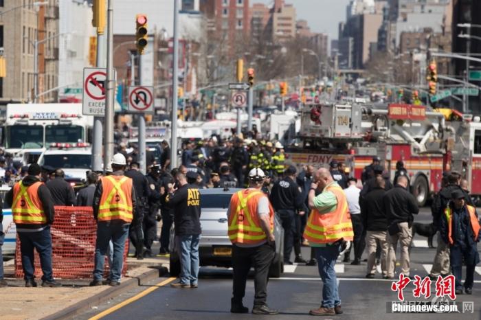 当地时间4月12日，美国纽约市布鲁克林区36街地铁站发生枪击案，至少16人受伤，其中10人直接中枪，大批警力和相关部门人员赶赴现场。图为地铁站外的地铁工作人员。 中新社记者 廖攀 摄