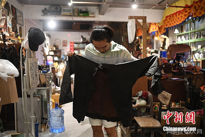 图为4月24日，武楷斯在“永续旧物”店整理淘到的香云纱。 中新社记者 陈楚红 摄