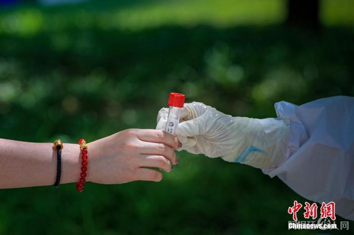 图为5月22日，一位北京市民将自己的病毒采样管交给医护人员。 中新社记者 贾天勇 摄