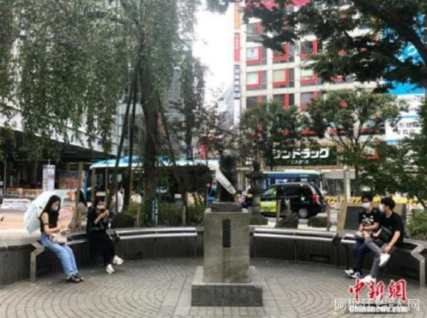 资料图：日本民众在涩谷车站前的雕塑旁休息。 中新社记者 吕少威 摄