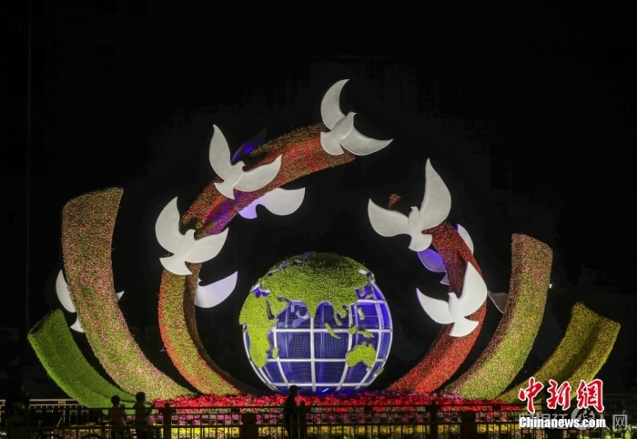 资料图：2022年9月26日晚，北京长安街沿线国庆主题花坛亮灯，市民在参观军事博物馆前广场布置的“命运共同体”花坛。 中新社记者 易海菲 摄