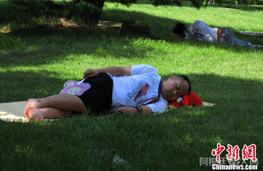 资料图：2010年南非世界杯，北京市民因熬夜观看比赛，在北京展览馆广场草坪树荫下长卧不起。中新社发 邹宪 摄