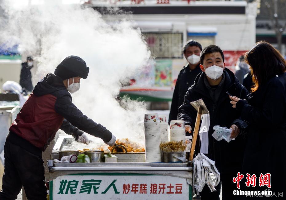 资料图:外出购物的市民购买品尝街头小吃。 刘新 摄 资料图:外出购物的市民购买品尝街头小吃。 刘新 摄