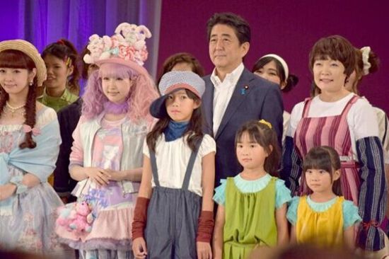 安倍昭惠身穿扎腿劳动裤，以“农家女孩”的形象同安倍手挽手同登舞台